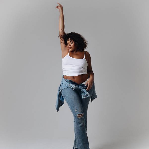 Modelo Rita usa top branco curto e calça jeans de cintura baixa. Na foto, ela está com as mãos levantadas e olhos fechados - Metrópoles