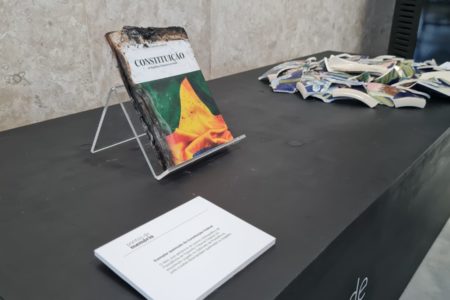 Exposição no plenário do STF com escombros e materiais danificados após invasões antidemocráticas feitas por bolsonaristas em janeiro. No detalhe, exemplar queimado da Constituição com cacos de um objeto quebrado ao lado - Metrópoles