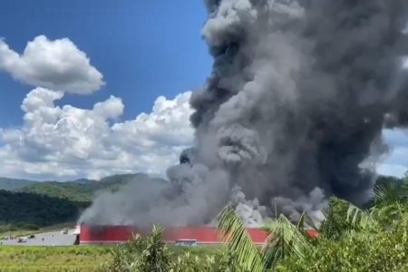 Imagem mostra incêndio num galpão em Brusque. Fumaça escura sai do local