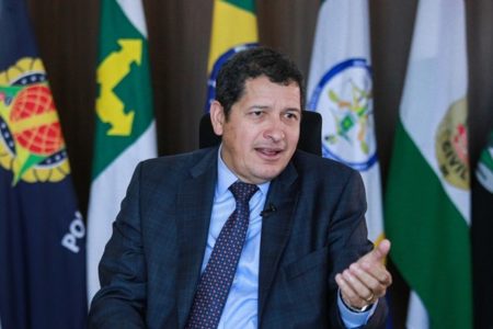 O novo secretário de segurança do Distrito Federal, Sandro Avelar, posa para foto em sua sala com bandeiras das forças de segurança do DF ao fundo. Ele fala gesticulando - Metrópoles