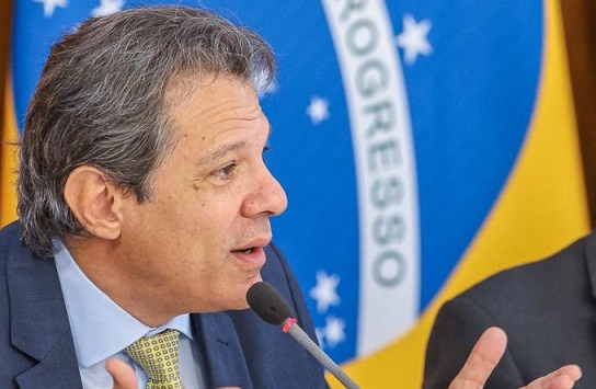O ministro da Fazenda, Fernando Haddad, em reunião com o presidente Lula e lideranças políticas no Planalto. Ele gesticula enquanto fala diante de microfone - Metrópoles