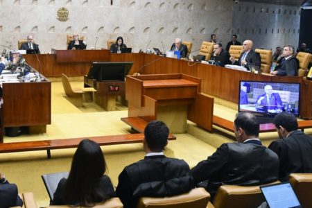 Ministros do STF votam em plenário sob a presidência de Rosa Weber. Em televisão mostrada ao auditório, aparece a fala do ministro Edson Fachin - Metrópoles