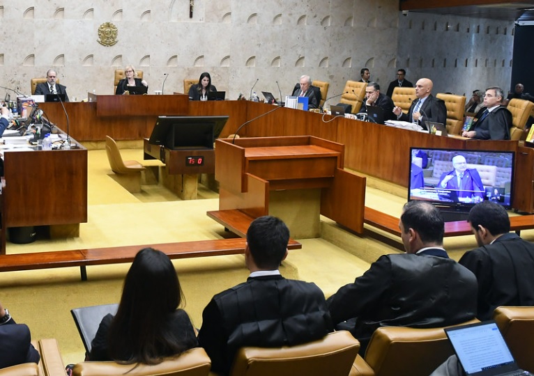 Ministros do STF votam em plenário sob a presidência de Rosa Weber. Em televisão mostrada ao auditório, aparece a fala do ministro Edson Fachin - Metrópoles