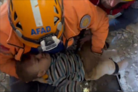 criança em colo de homem com capacete de proteção laranja