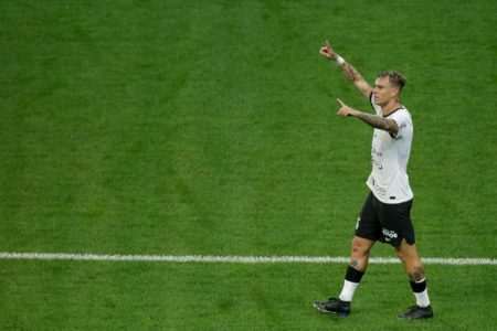 Roger Guedes com os braços levantados em campo