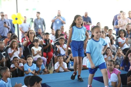 A governadora Celina Leão entrega uniformes com modelo novo para alunos da rede pública. No detalhe, meninas desfilam com as roupas novas em palco - Metrópoles