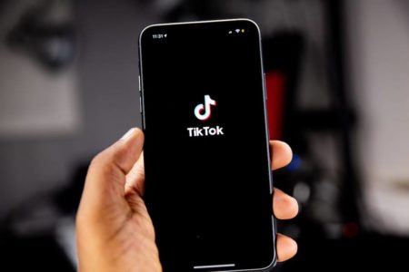 Mão branca segurando um celular com a logo do TikTok - Metrópoles