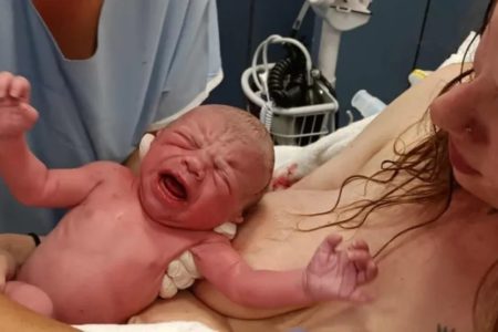 Foto de uma mulher segurando um bebê durante seu nascimento após ter dado à luz