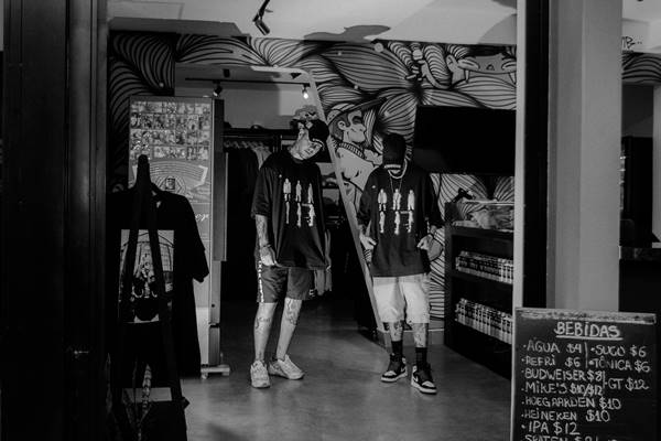 Dois homens com camisetas pretas posando para fotos de moda - Metrópoles