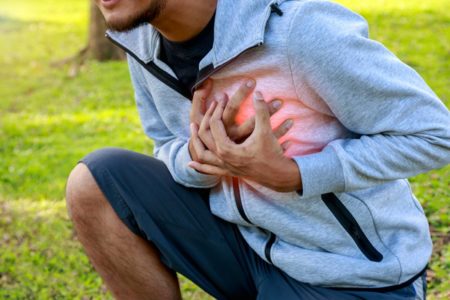 Pessoa jovem agachada com as mãos levadas ao peito