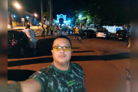 hoomem tira selfie com camiseta camuflada em frente a manifestação