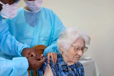 Foto colorida de uma idosa recebendo a vacina bivalente da Covid-19 - Metrópoles