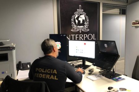 Policial Federal diante de símbolo da interpol - brasileiros - brasil - portugal - metrópoles