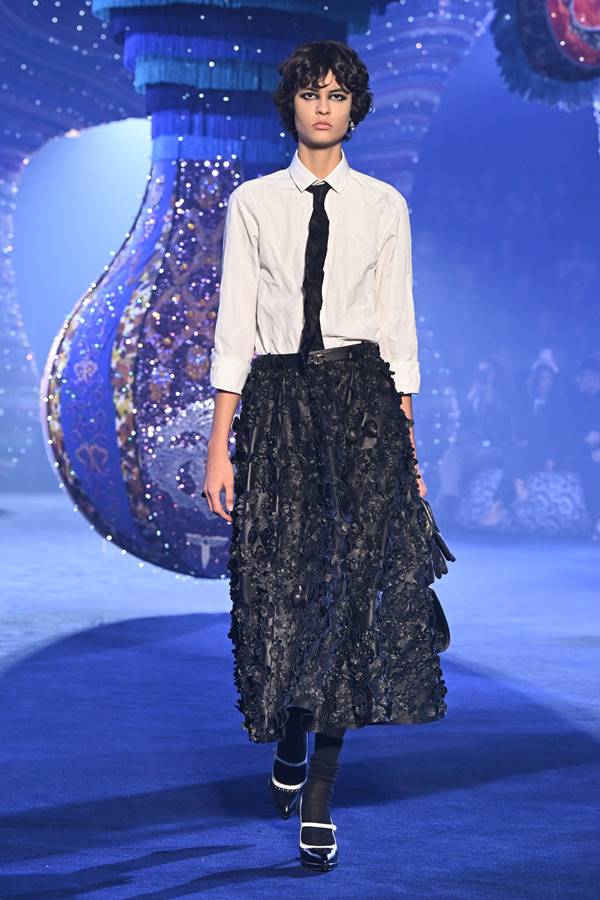 Modelo da Dior usa camisa branca, gravata, saia e sandália de salto alto com meias - Metrópoles