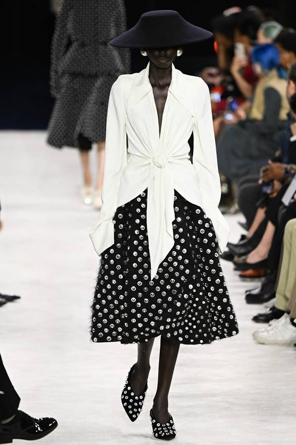 Modelo negra da Balmain usa sai de poá, blusa branca com amarração e chapéu preto - Metrópoles