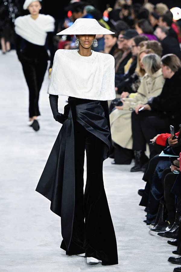 Modelo negra da Balmain usa calça preta, blusa branca e chapéu branco - Metrópoles