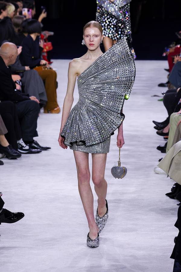 Modelo branca da Balmain usa vestido com drapeado metálico e sandálias prateadas - Metrópoles