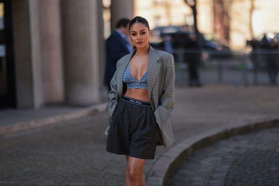 Mulher posando para foto em calçada na rua. Ela está com as mãos no bolso do blazer - Metrópoles