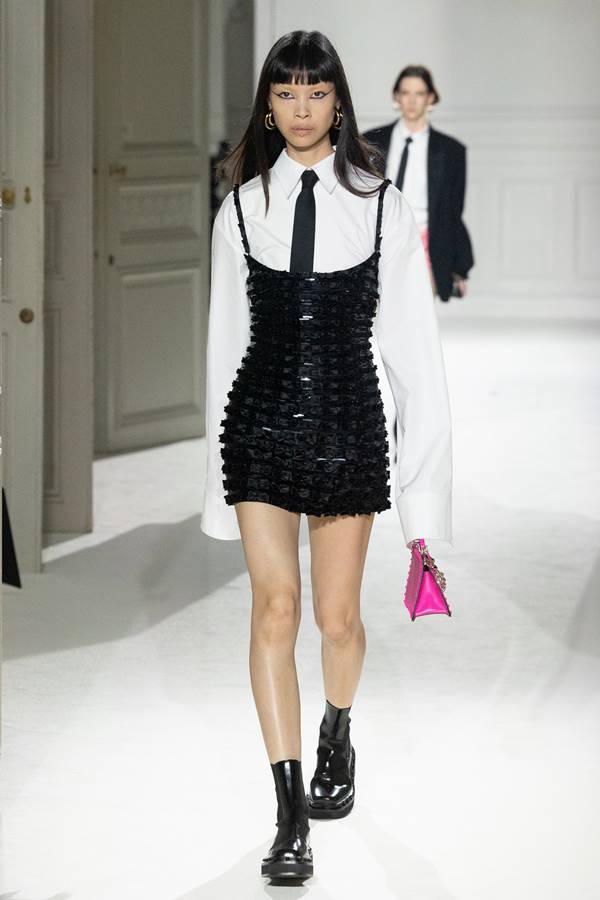Modelo asiática usa vestido preto, camisa brana e gravata