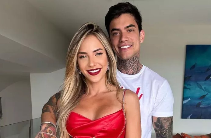 Foto colorida de Gabi Martins e Lincoln Lau. Ela é loira, tem olhos claros e está usando um vestido vermelho. Ele é branco, tem cabelo preto e está utilizando uma camisa branca - Metrópoles