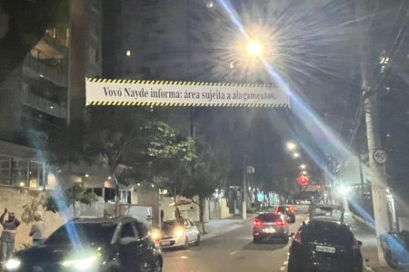 Imagem colorida mostra faixa colocada por familiares de vítima de afogamento após enchente em SP com aviso sobre alagamentos em rua - Metrópoles