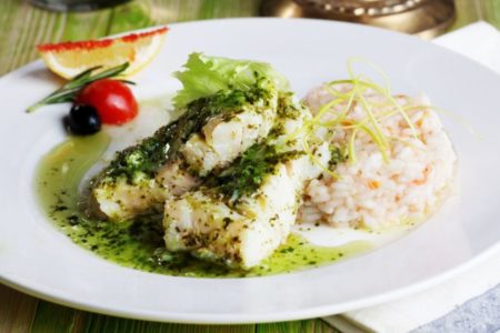 peixe bacalhau em um prato branco com arroz e tomate ao molho verde - metrópoles