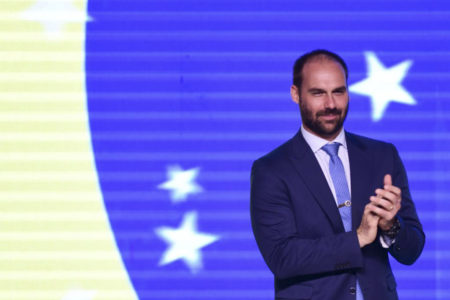 Deputado Federal Eduardo Bolsonaro com bandeira do Brasil ao fundo durante cerimônia de transmissão de cargo à nova presidente do PL Mulher, Michelle Bolsonaro em brasília - Metrópoles