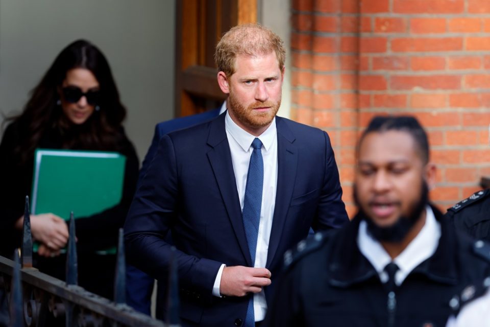 Foto colorida de homem branco, ruivo, vestido com blazer azul andando ao redor de pessoas - Metrópoles