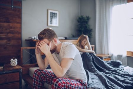 Imagem colorida: casal sentado em cama - Metrópoles