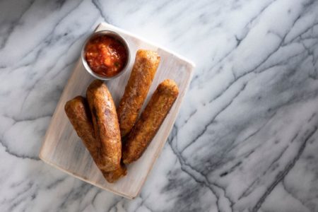 Salsicha vegana recheada com grão-de-bico, paprica algo e outros tempeiros com molho de tomate dentro de um prato branco - Metrópoles