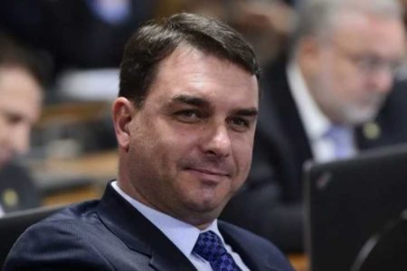 Foto colorida do senador Flávio Bolsonaro sentado, de terno e gravata no auditório do Senado - metrópoles