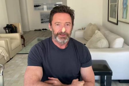 Ator Hugh Jackman com curativo na ponta do nariz olhando para a câmera