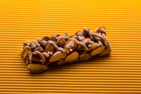 Imagem, em fundo amarelo, de uma barra de cereais - Metrópoles