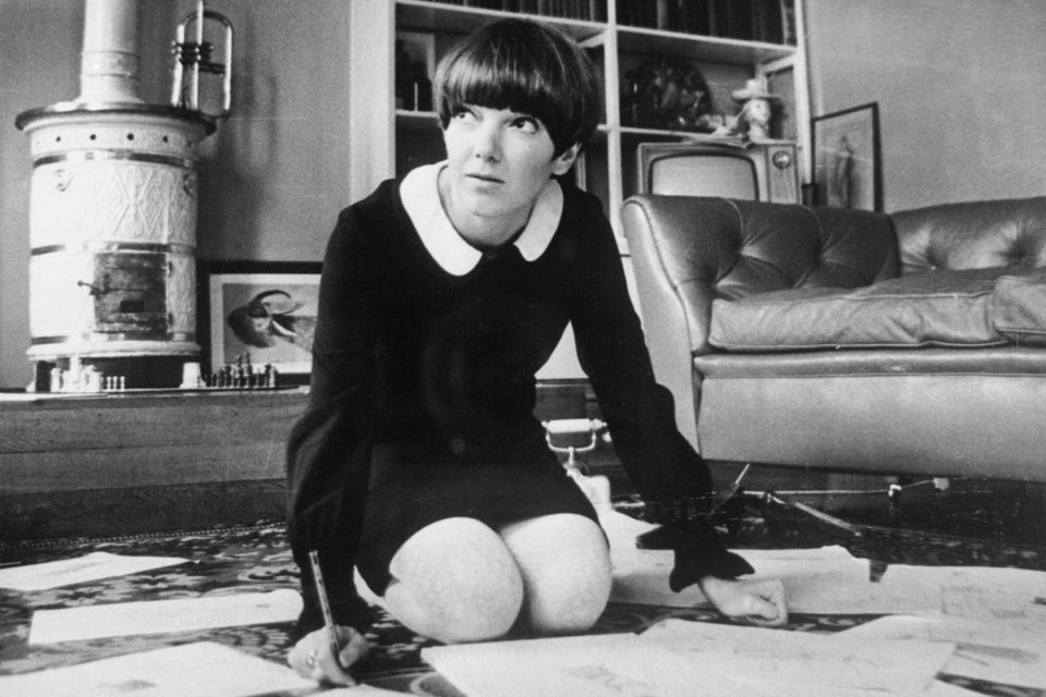 Estilista Mary Quant, em 1965. Na imagem em preto e branco, ela está de joelho no chão com papéis a sua volta - Metrópoles