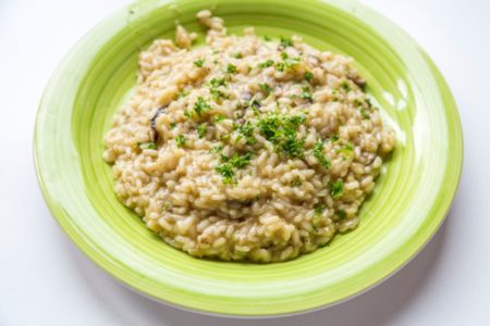 Risoto de Cogumelo em um prato verde com salsa por cima - metropoles