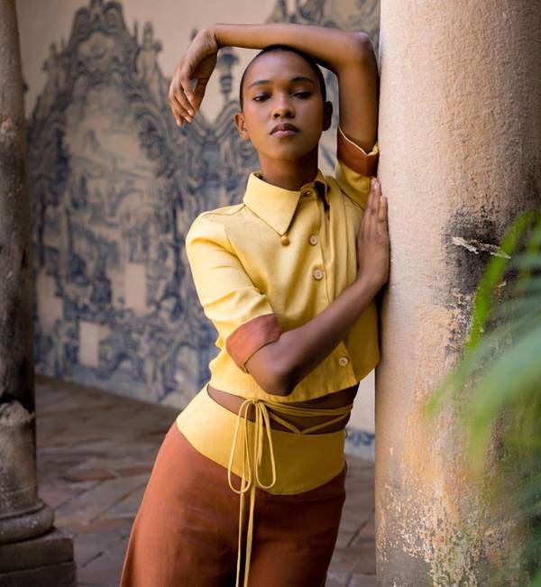 Modelo negra posa com look amarelo apoiada em pilastra - Metrópoles