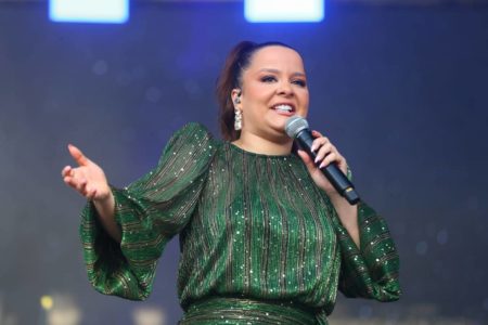 Foto colorida cantora maiara de vestido verde cantando em microfone - metrópoles