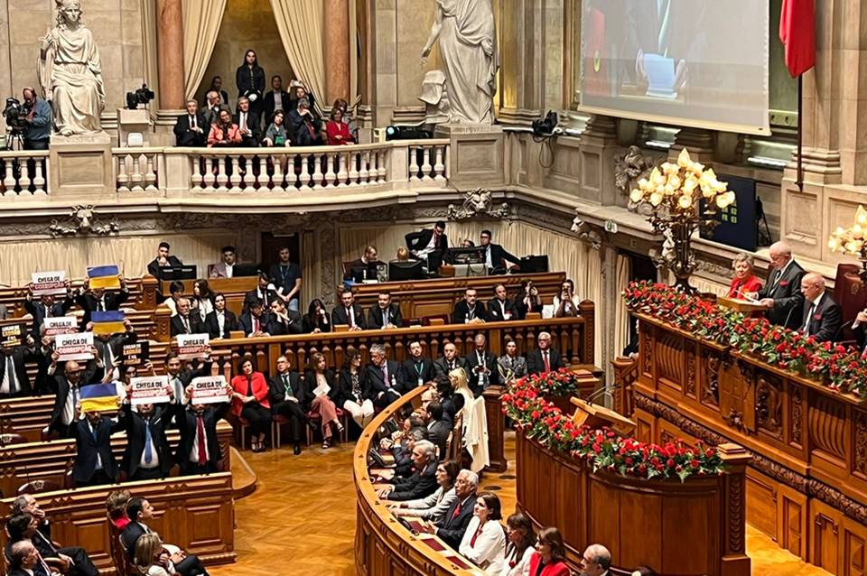 Imagem colorida mostra Lula discursando e parlamentares portugueses com bandeiras da Ucrânia em protesto - Metrópoles