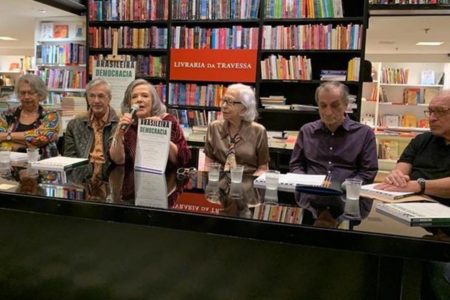 Imagem de um grupo de escritores sentados à uma mesa - Metrópoles