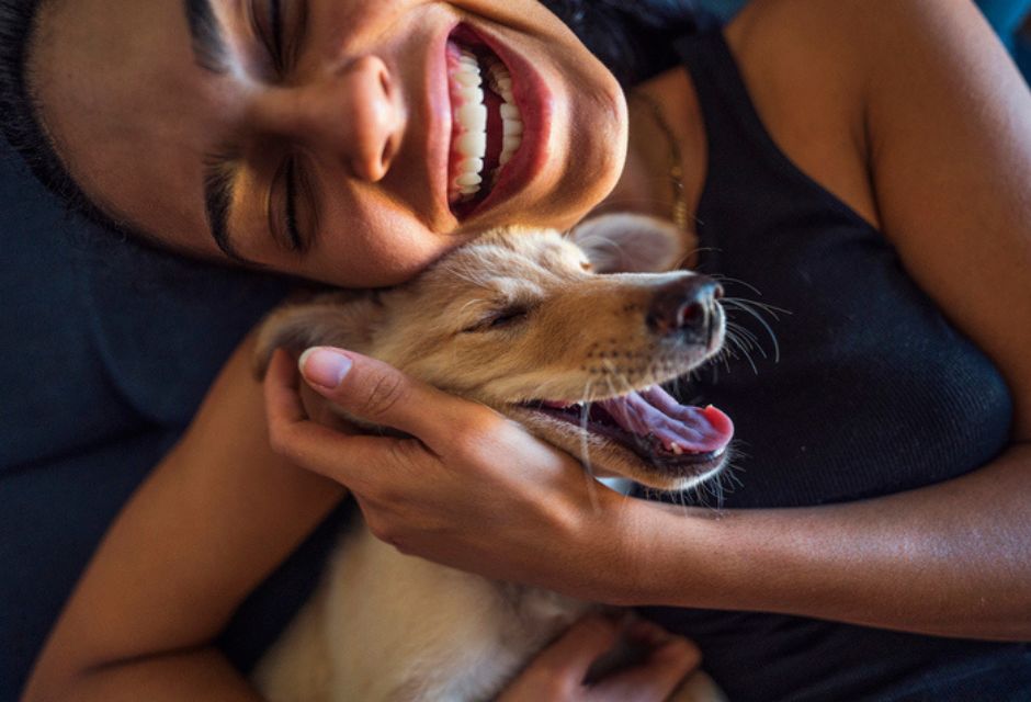 Mulher com cachorro se abraçando e sorrindo - metrópoles