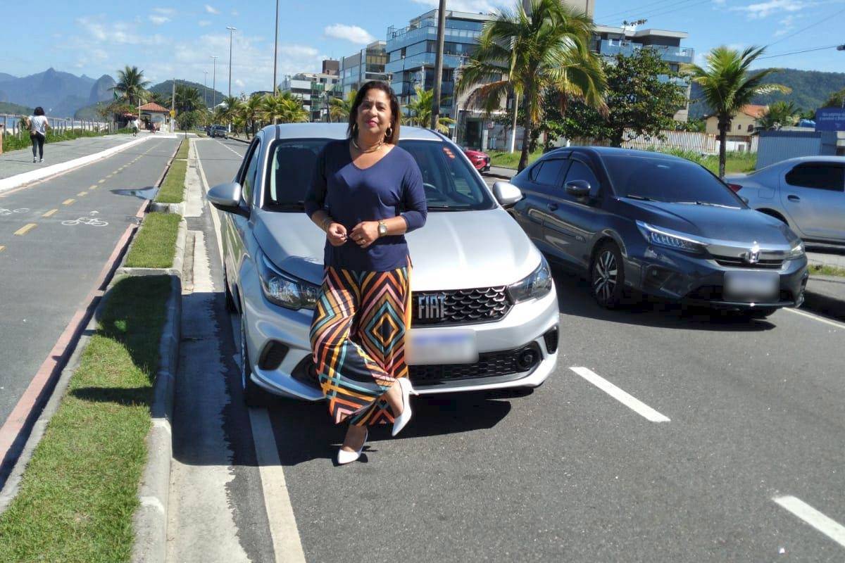 Fotografia colorida de mulher de braços cruzados encostada no capô de carro-Metrópoles