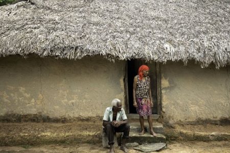 imagem colorida com um casal de quilombolas em frente a uma casa de palha - Metrópoles