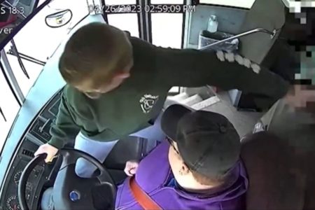 Imagem colorida: garoto segura volante de ônibus ao lado de motorista - Metrópoles