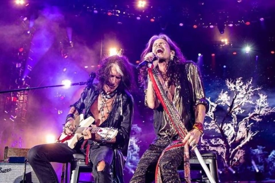 foto colorida de dois homens cantando em palco - metrópoles