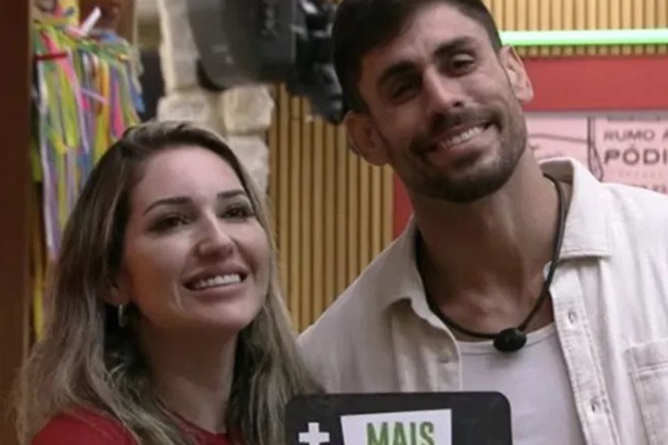 Cara de Sapato e Amanda no BBB23. Ele está de camisa roupa clara e com o microfone exposto. Ela está com uma roupa vermelha - Metrópoles