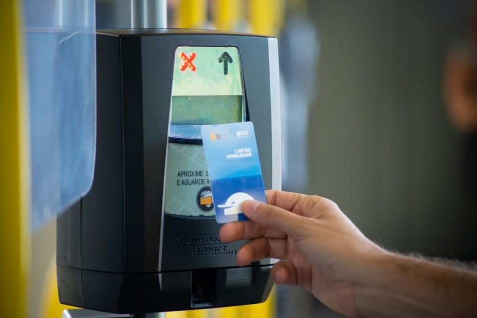 Passageiro de ônibus passando cartão no validador