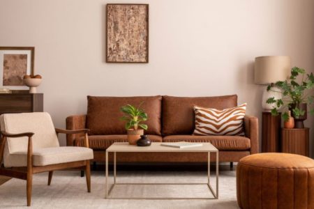 decoração da sala com tons terrosos no sofa, cadeira e quadros - metropoles