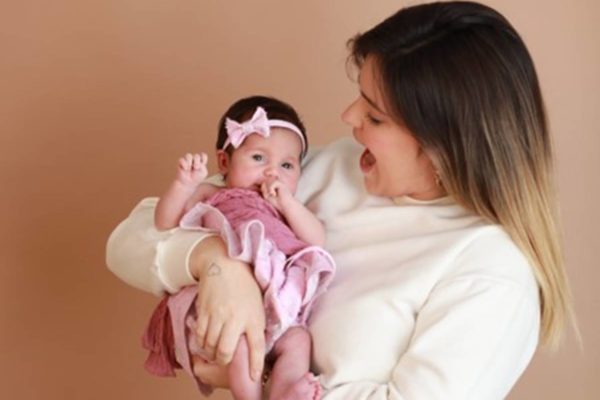 Foto colorida de Viih Tube, de casaco branco, e Lua. A filha está no colo da mãe, com roupinha rosa - Metrópoles