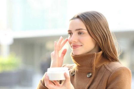 mulher no outono usando creme no rosto para cuidados - Metrópoles