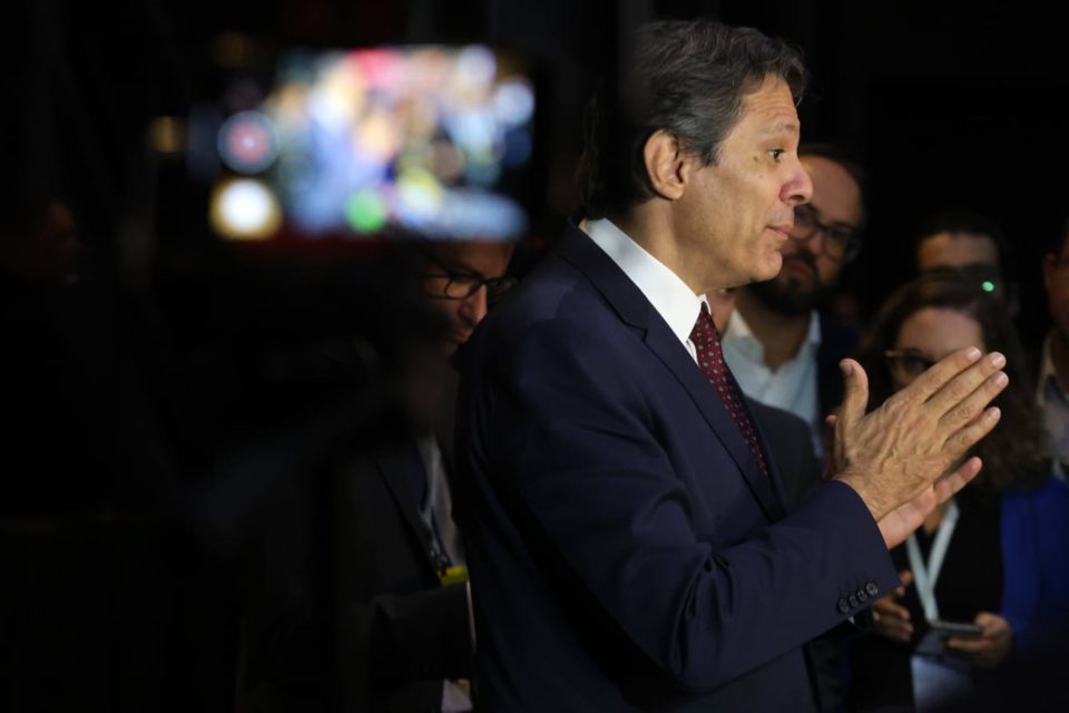 Imagem colorida do ministro Fernando Haddad concedendo entrevista com jornalistas ao fundo - Metrópoles